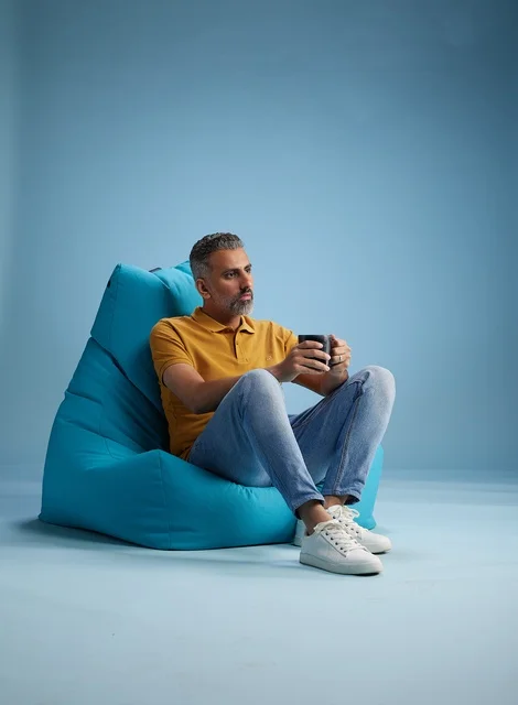 Saudi Man Relaxing on Blue Bean Bag with Coffee Mug