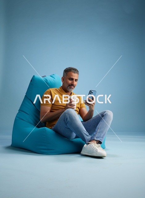 رجل سعودي يسترخي على كرسي بين باج مع هاتف