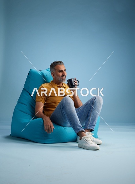 رجل سعودي يجلس على كرسي بين باج مع كوب قهوة