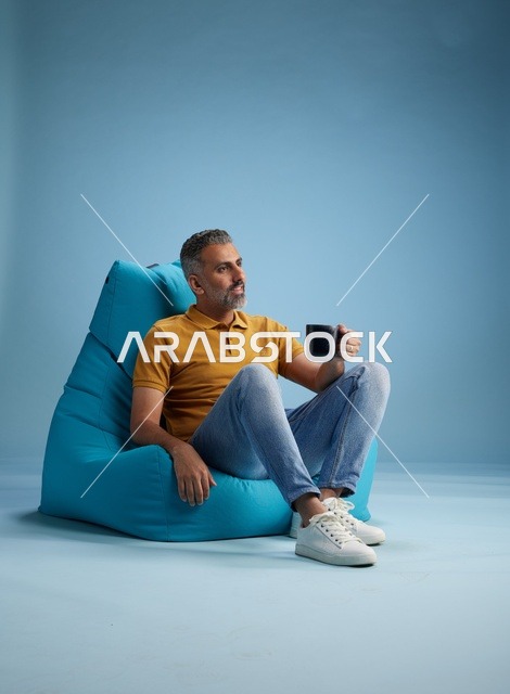 رجل سعودي يسترخي على كرسي بين باج مع قهوة