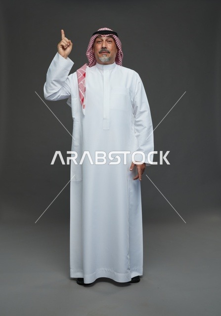 رجل سعودي بالزي التقليدي يشير للأعلى
