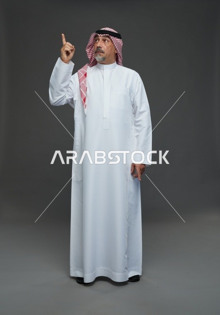 Saudi Man in Traditional Dress Pointing Upwards Studio
