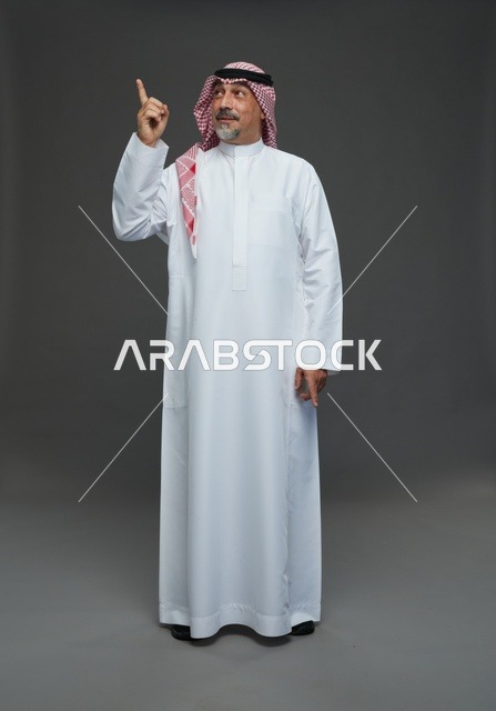 رجل سعودي بالزي التقليدي يشير إلى الأعلى