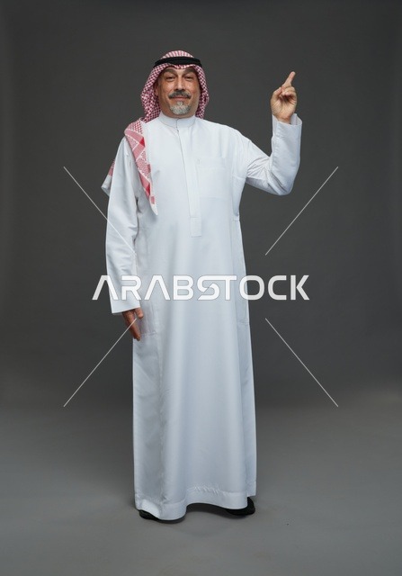 رجل سعودي بالثوب التقليدي يشير إلى الأعلى