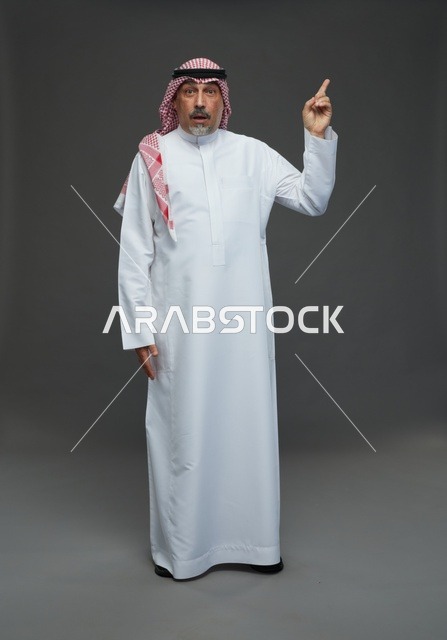 رجل سعودي بالزي التقليدي يشير للأعلى بدهشة