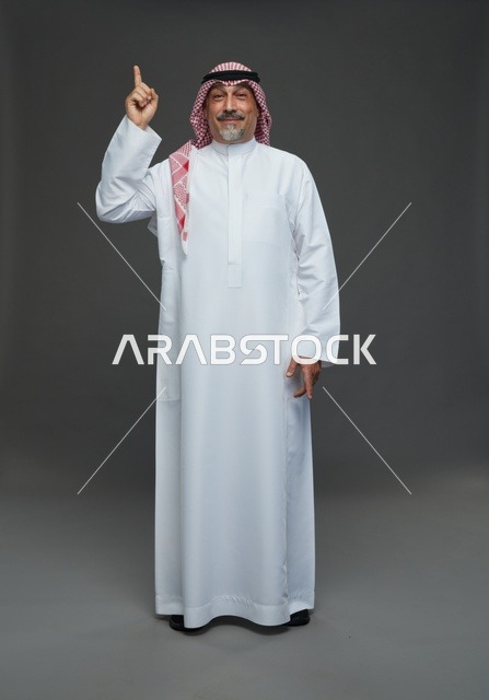 رجل سعودي بالزي التقليدي يشير إلى الأعلى