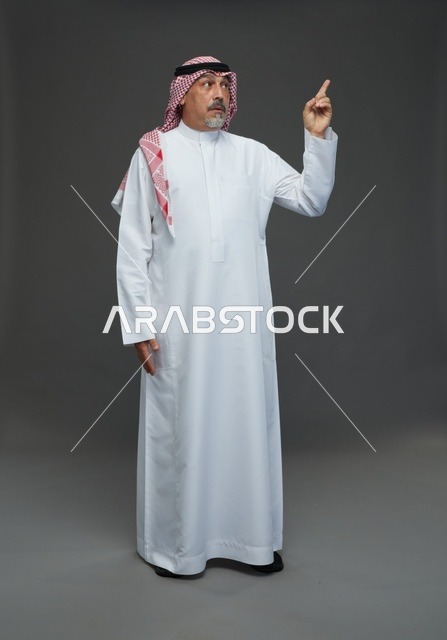 رجل سعودي بالزي التقليدي يشير للأعلى
