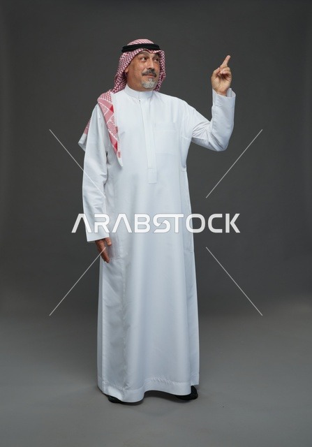 رجل سعودي بالزي التقليدي يشير للأعلى داخل استوديو