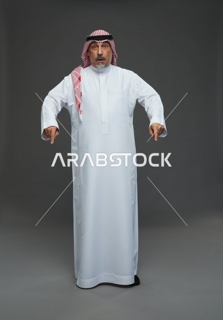 رجل سعودي بالزي التقليدي يشير للأسفل بتعبير مندهش