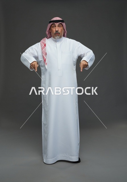 رجل سعودي بالزي التقليدي يشير إلى الأسفل