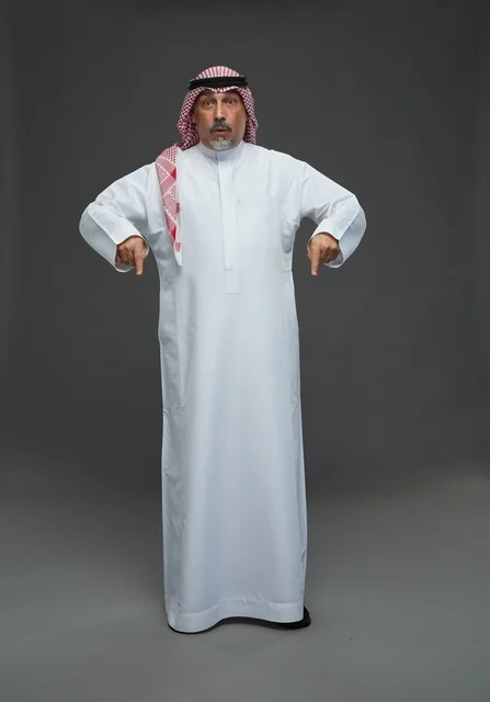 رجل سعودي بالزي التقليدي يشير إلى الأسفل رجل سعودي بالزي التقليدي يشير إلى الأسفل
