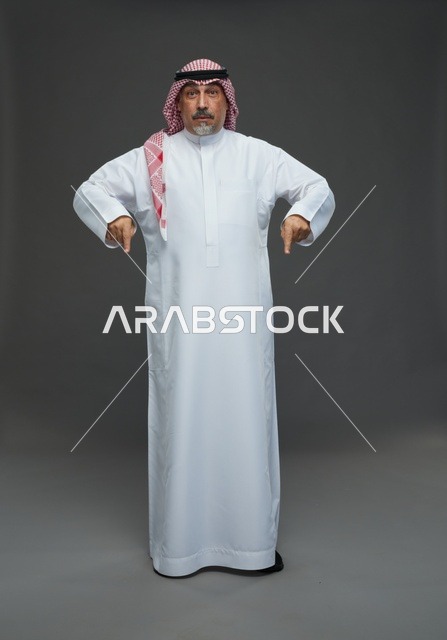 رجل سعودي بالزي التقليدي يشير إلى الأسفل