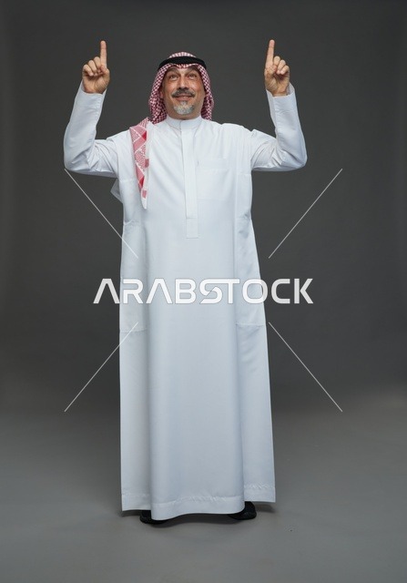 رجل سعودي بالزي التقليدي يشير إلى الأعلى
