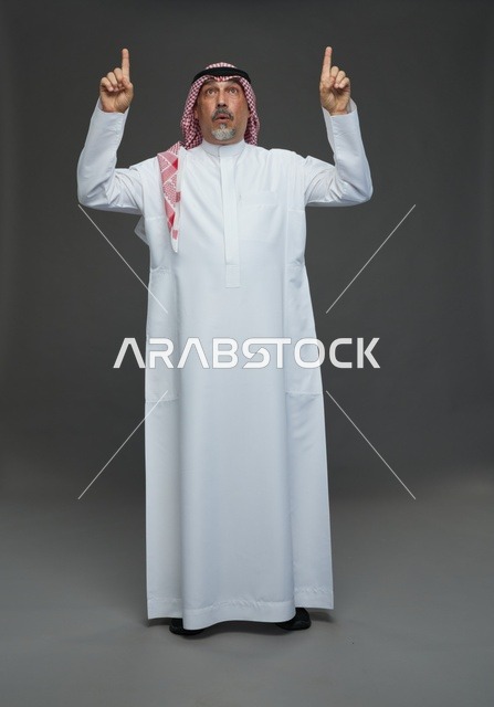 رجل سعودي بالزي التقليدي يشير إلى الأعلى