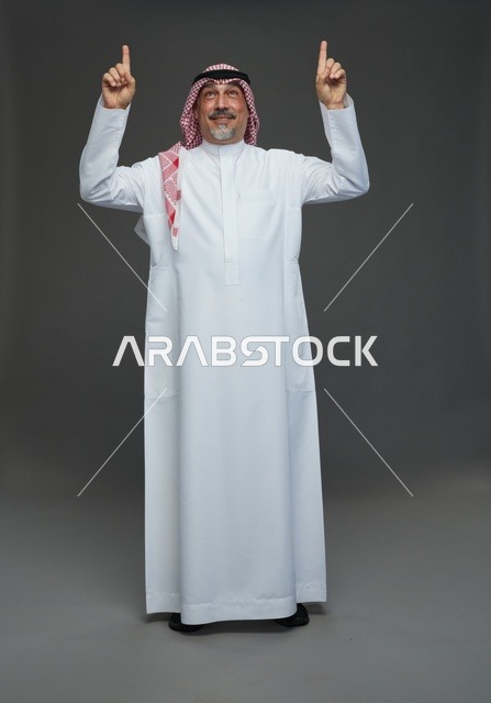 رجل سعودي بالزي التقليدي يشير إلى الأعلى