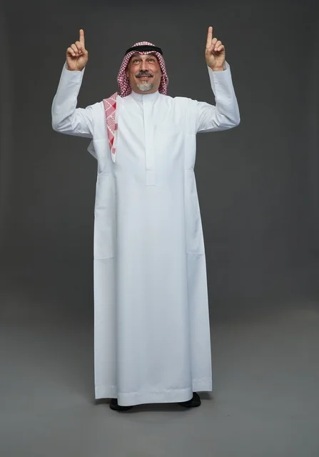 رجل سعودي بالزي التقليدي يشير إلى الأعلى
