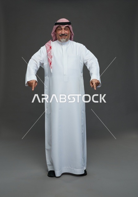رجل سعودي بالزي التقليدي يشير إلى الأسفل نحو الأرض