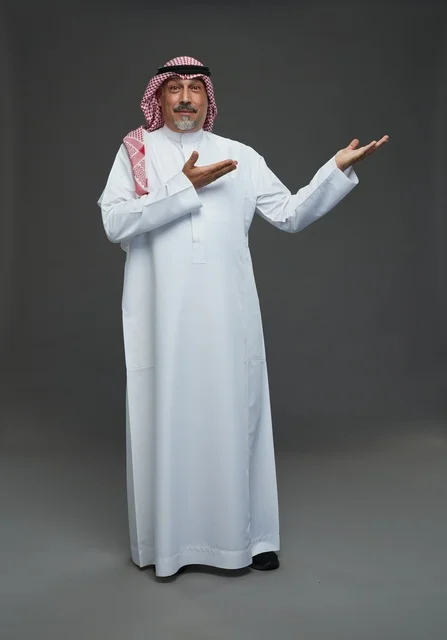 رجل سعودي بالزي التقليدي يشير بيده في الاستوديو
