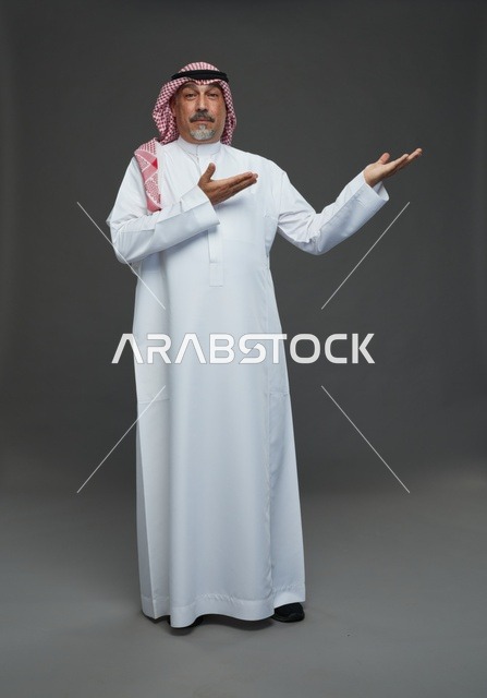 Saudi Man in Traditional Dress Pointing on Gray Background