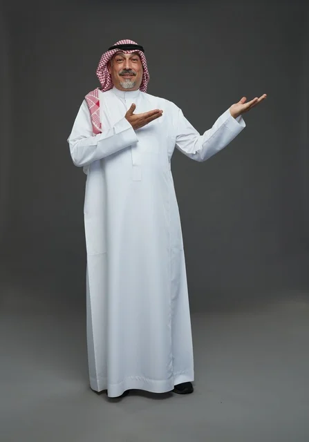 رجل سعودي بالزي التقليدي يشير بيده في استوديو