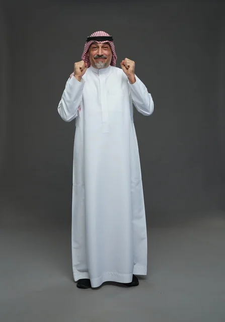 رجل سعودي بالزي التقليدي يحتفل بالنجاح في استوديو