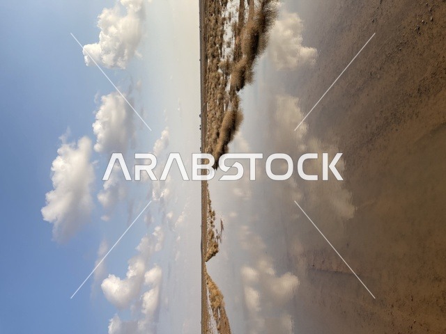 انعكاس مياه السيول في الصحراء تحت الغيوم