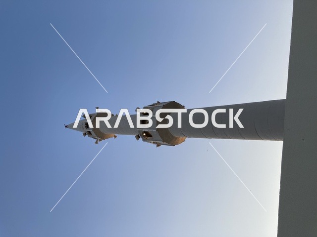 مئذنة مسجد بيضاء تحت سماء زرقاء صافية