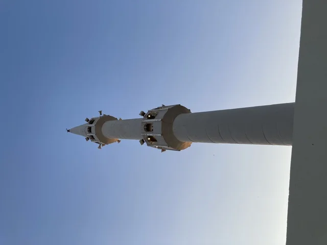 مئذنة مسجد بيضاء تحت سماء زرقاء صافية