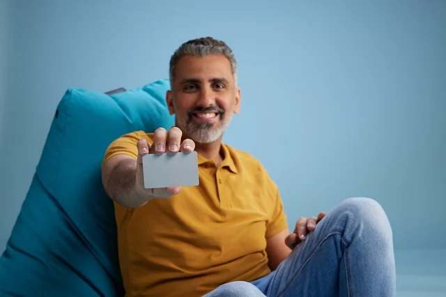 رجل سعودي يحمل بطاقة ائتمان على كرسي بين باق