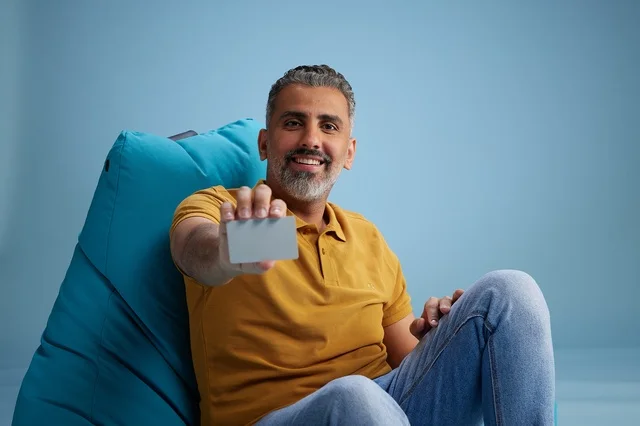 Saudi Man Holding Blank Card on Bean Bag Chair