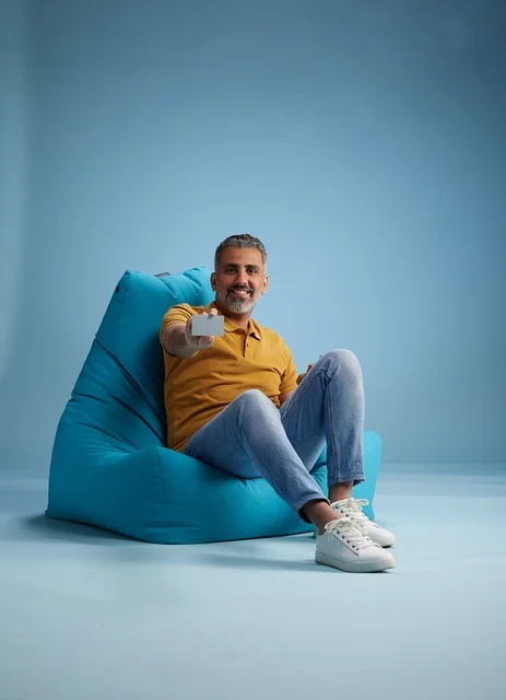 رجل سعودي يحمل بطاقة ائتمان على كرسي بين باق