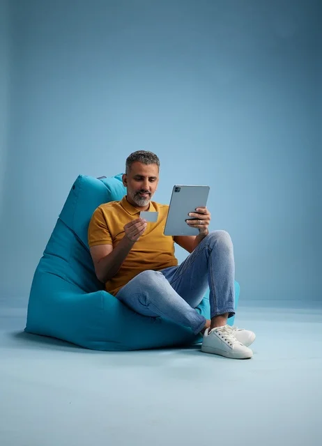 رجل سعودي يستخدم جهاز لوحي وبطاقة ائتمان للتسوق الإلكتروني