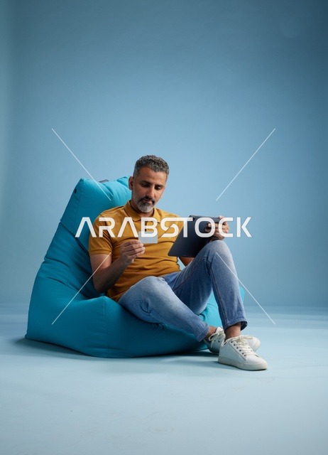 رجل سعودي يستخدم بطاقة ائتمان وجهاز لوحي للتسوق