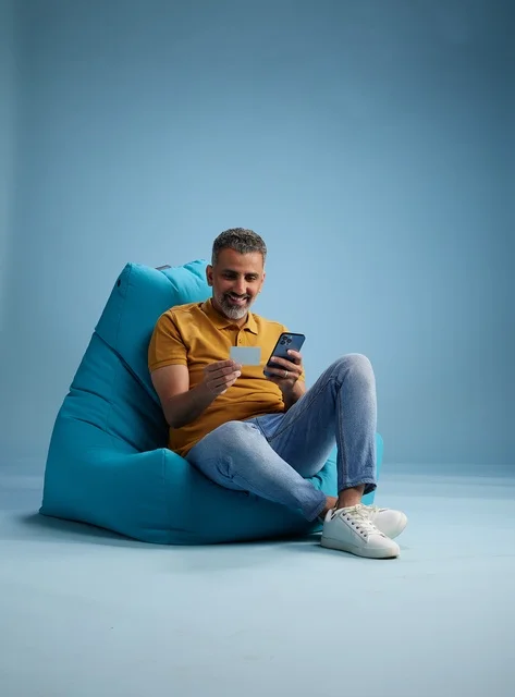 Saudi Man Using Credit Card and Smartphone on Beanbag