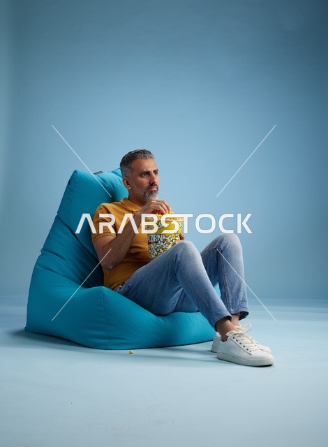 رجل سعودي يأكل الفشار على كرسي بين باج