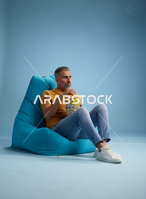 رجل سعودي يأكل الفشار على كرسي بين باج