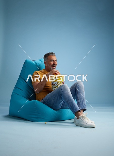 رجل سعودي يأكل الفشار على كرسي بين باج