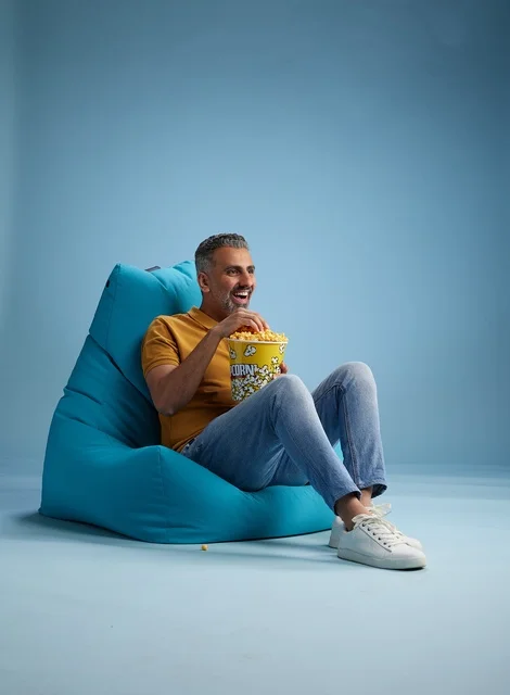 رجل سعودي يأكل الفشار على كرسي بين باج