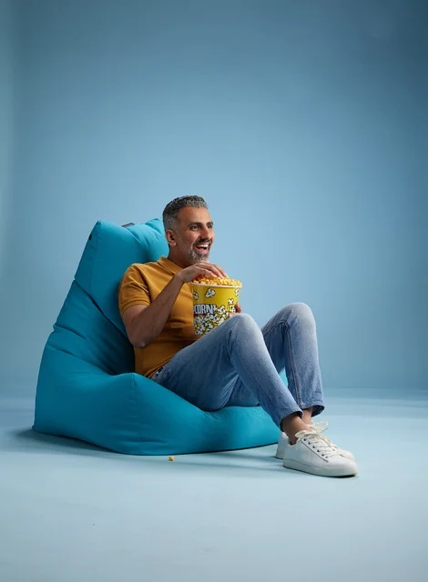 Saudi Man Eating Popcorn on Blue Beanbag in Studio