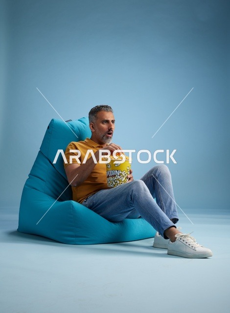 رجل سعودي على كرسي بين باج يأكل الفشار