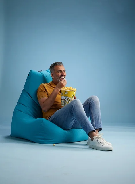 رجل سعودي يأكل الفشار على كرسي بين باج