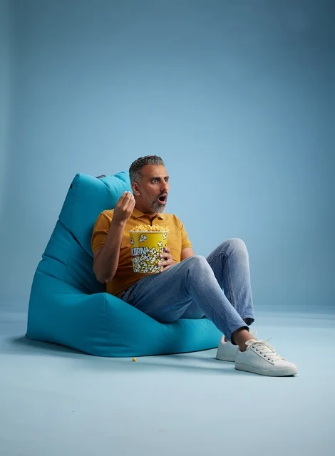 Saudi Man Eating Popcorn in Bean Bag Blue Background