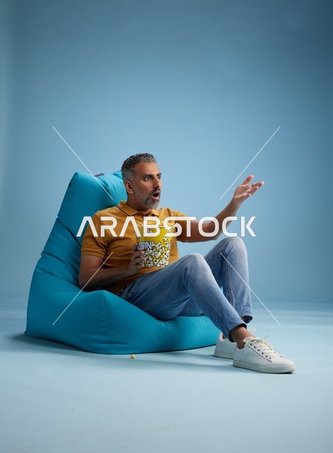 رجل سعودي يأكل الفشار مع تعبير وجه مندهش