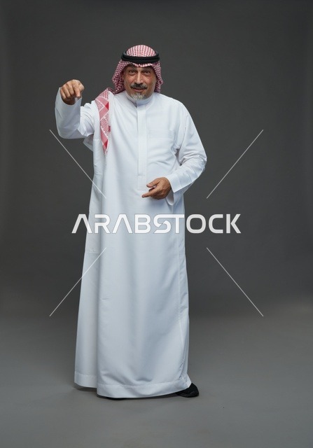 رجل سعودي بالزي التقليدي يشير بإصبعه في الاستوديو