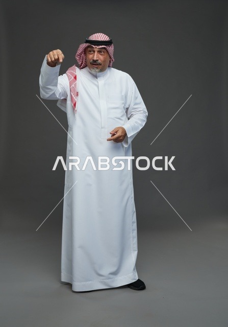 رجل سعودي بالزي التقليدي يشير بيده في استوديو