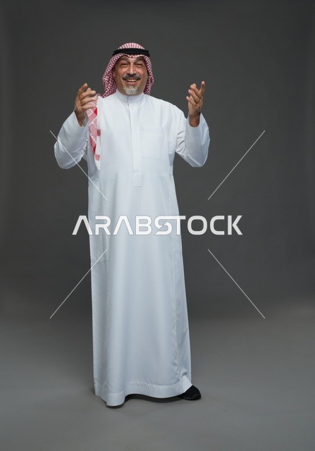 رجل سعودي بالزي التقليدي في استوديو بخلفية رمادية