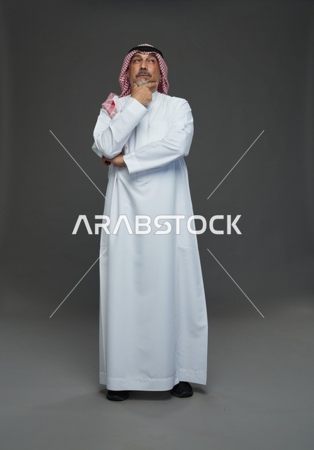 رجل سعودي بالزي التقليدي في استوديو بوضعية تفكير