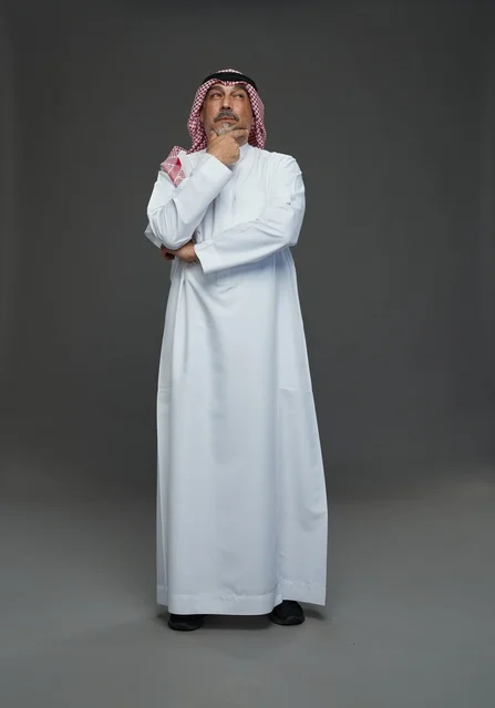 رجل سعودي بالزي التقليدي في استوديو بوضعية تفكير