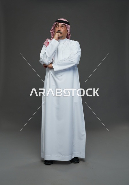 رجل سعودي بالزي التقليدي والشماغ في وضعية تفكير