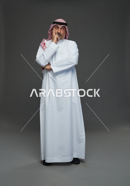 Saudi Man in Traditional Dress Pondering on Gray Background